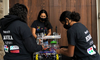 3 members of Riverdale High School Robotics Team working on robot